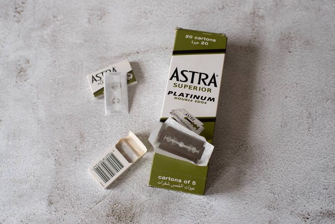 A box of Astra Superior Platinum double-edge razor blades (20 cartons) with an open individual carton showing a single blade